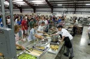 Inside of a dining facility with hundreds of students being served food.